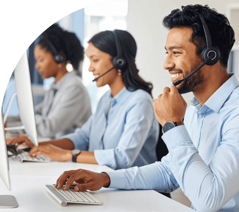 Equipe de atendentes e recepcionistas sorrindo enquanto utilizam headsets em seus computadores, representando a melhoria na experiência do paciente, a organização dos canais e a redução do tempo de espera.